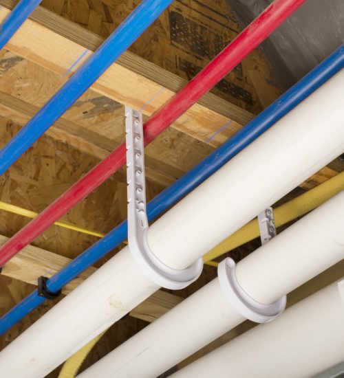 PEX and drain pipes attached to the basement ceiling of a home.